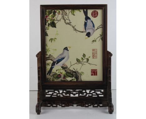 A Chinese carved wood table screen, of fret work design supporting a double sided silk work panel of embroidered birds, 3 red