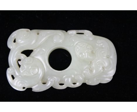 A Chinese greenish white jade pendant carved as a scrolling dragons about a circular centrally placed hole 7.3cm max