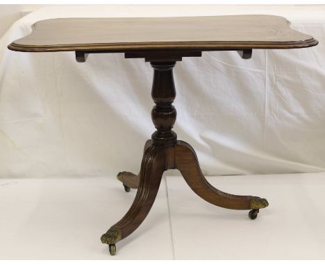 A mahogany tilt top table, shaped rectangular top with stepped edge on tripod reeded base, with lion paw  terminals and caste