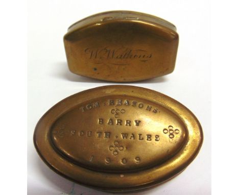 A MINER'S BRASS TOBACCO OR SNUFF BOX of elongated oval form, the lid impressed 'TOM. REASONS. / BARRY / SOUTH WALES / 1909', 