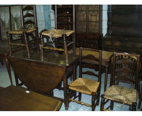 An 19th Century oak drop leaf dining table and four conforming rush seated ladder back kitchen chairs.