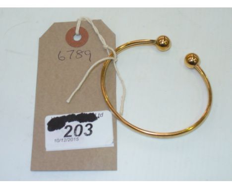 A 9ct Gold bangle with sphere terminals.