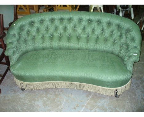 A Victorian green damask button back kidney shaped sofa raised on ebonised ring turned supports.
