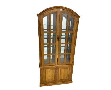 Light oak arched top display cabinet, mirrored interior enclosed by two glazed doors, double panelled cupboard below, on plin