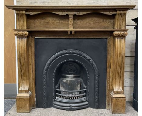 20th century fireplace, oak surround with moulded and scroll carved upright pilasters, with Victorian style cast iron inset a