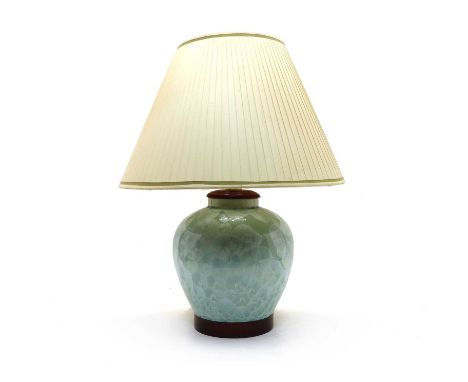 A modern green-glazed porcelain table lamp, with floral detail and wooden mounts, 28cm diameter, 40cm high, with a pleated si