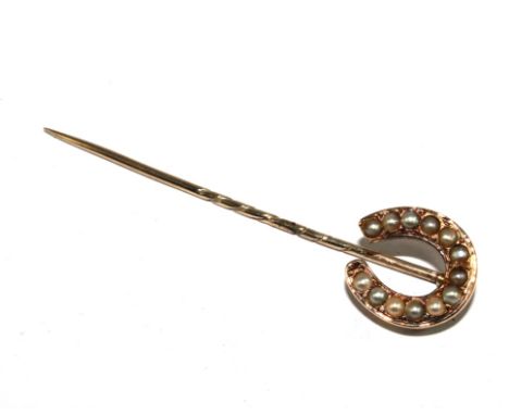A stick pin with a pearl set horse shoe