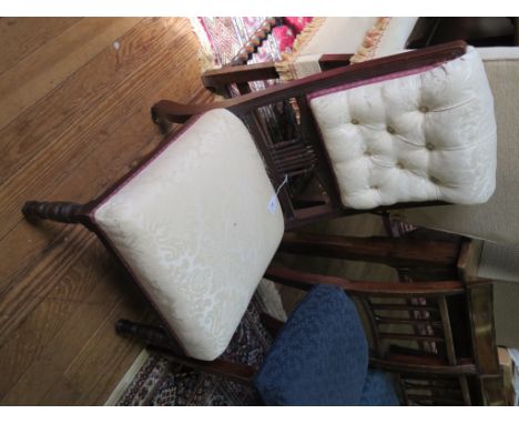 An Edwardian walnut fireside chair, with button upholstered and spindle back, stuffover seat and ring turned legs with pot ca