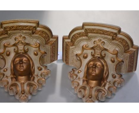 A pair of parcel-gilt plaster wall brackets, c. 1900, each with shaped shelf above a female mask within c-scrolls. 27cm by 30