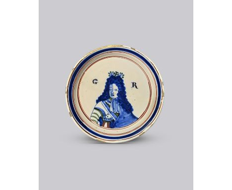 GEORGE I A London delftware plate, c.1714-27, painted in blue, green and red with a half-length crowned portrait flanked by t