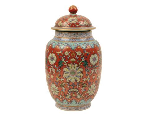 A CHINESE RUBY-GROUND LIDDED JAR enamelled in polychrome with scrolling lotus and fish within formalised borders, the base wi