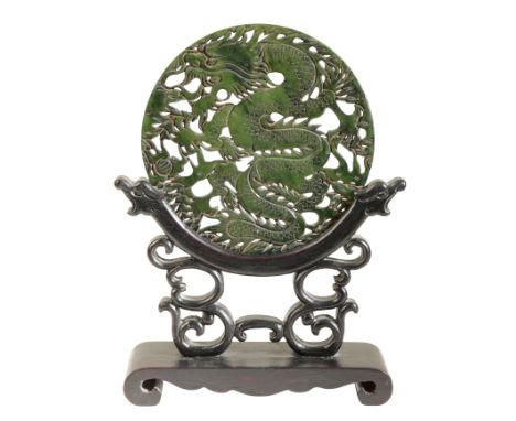 A CHINESE DARK GREEN BOWENITE CIRCULAR PLAQUE mounted on a wooden stand as a table screen, 21cm high