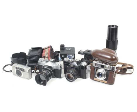 An assortment of cameras and accessories. To include a Voigtlander Vito CD, an Olympus Newpic Zoom 600, Two Zenit E's, a Heli