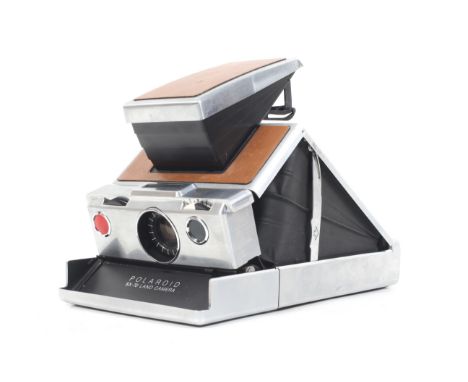 A Polaroid SX-70 Land Camera. Tan and chrome. Together with a case and instructions.