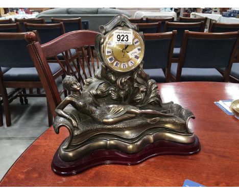A decorative mantel clock featuring a reclining lady