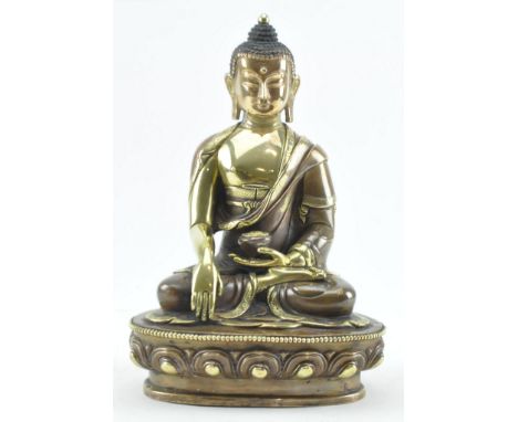 A brass and copper figure of seated Shakyamuni.&nbsp;His hair is arranged in tight curls over the high ushnisha topped by a j