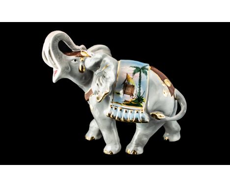 Porcelain Figure of an Elephant with trunk raised, and decorative gilt and coloured highlights on the rug across the elephant