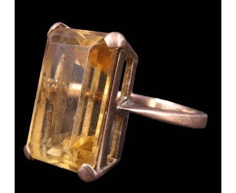 A 1970s citrine dress ring, the 17.5 x 11.5 mm emerald cut stone set on an open gallery between tapering shoulders in a 9 ct 