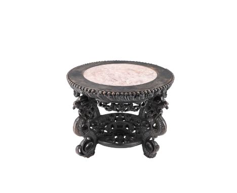 A Chinese carved hardwood stand, having an inset variegated pink marble top and carved base shelf raised on dragon-form suppo