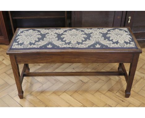 An Edwardian walnut piano bench, having a hinged upholstered seat, 99 x 39 x 52 cm