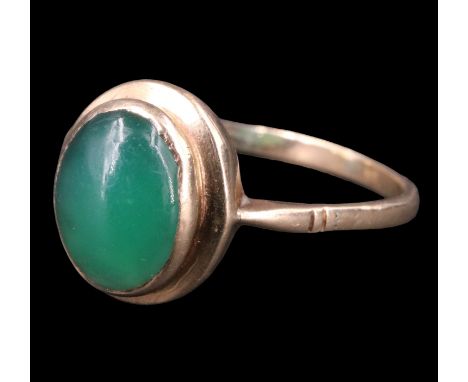 A 1970s green jade finger ring, having a 11 x 7.5 mm cabochon bezel set between tapering shoulders in a 9 ct gold shank, Lond