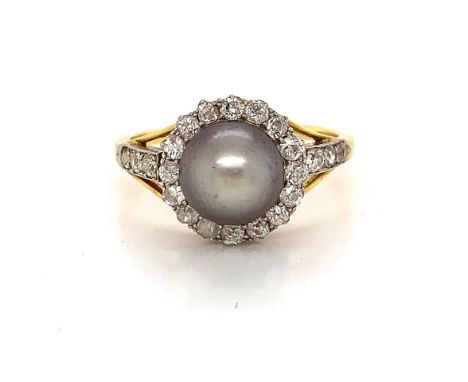 A CULTURED PEARL AND DIAMOND YELLOW METAL RING. THE GREY 8.5mm CULTURED PEARL SITS IN THE CENTRE OF A DIAMOND HALO, FLANKED B