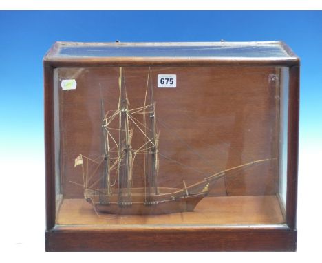 A MAHOGANY SCALE MODEL OF A THREE MASTED SHIP FLYING THE ROYAL NAVY WHITE ENSIGN AT ITS STERN AND IN GLAZED MAHOGANY CASE.   