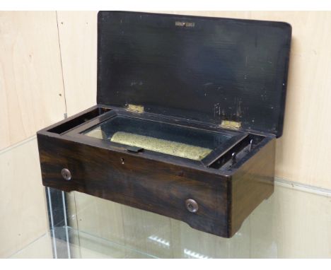 A ROSEWOOD CASED MUSIC BOX PLAYING AIRS ON A 21cms. COMB, THE BOX LID INLAID WITH MUSICAL TROPHY ENCLOSED BY BOX WOOD STRINGI