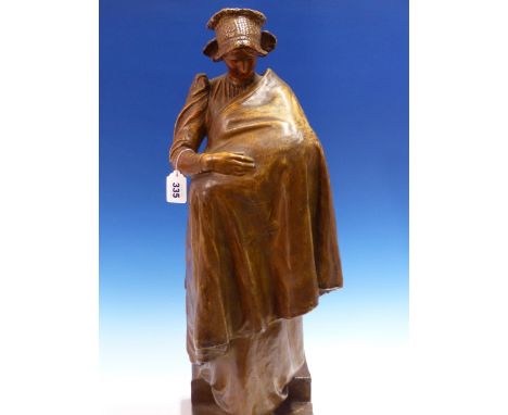 A BRONZED TERRACOTTA FIGURE POSSIBLY BY GOLDSCHEIDER OF A MOTHER WEARING A LACE HAT AND CARRYING HER CHILD UNDER A DRAPE WORK