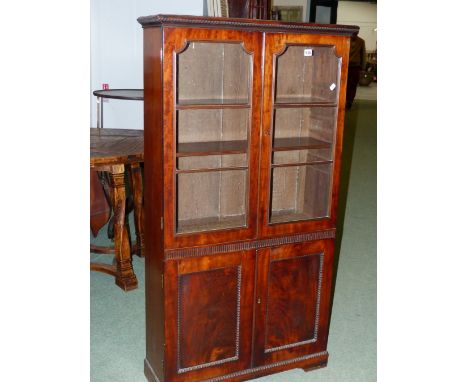 A MAHOGANY BOOK CASE, THE RECTANGULAR TOP OVER DOORS GLAZED WITH  THREE PANELS OVER TWO ADJUSTABLE SHELVES, THE BASE WITH REE