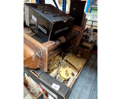 A box of clock parts together with a wall clock and a cuckoo clock. 