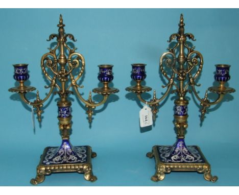 A pair of Limoges style enamel and gilt metal two branch candelabra, on a square base, 34.5 cm high (some repair) (2)