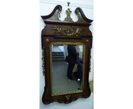 A George III style mahogany and carved giltwood mirror, with a swan neck pediment above a frieze applied a ribbon tie and fol