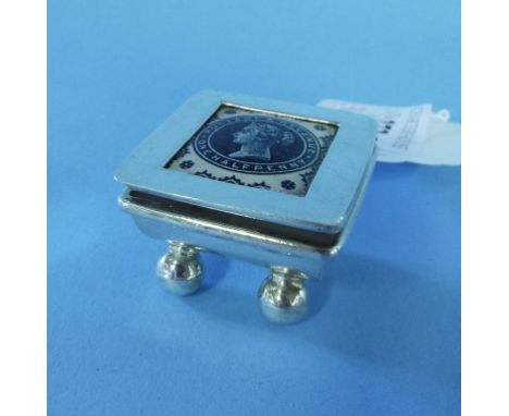 A silver coloured metal box, decorated an enamel stamp