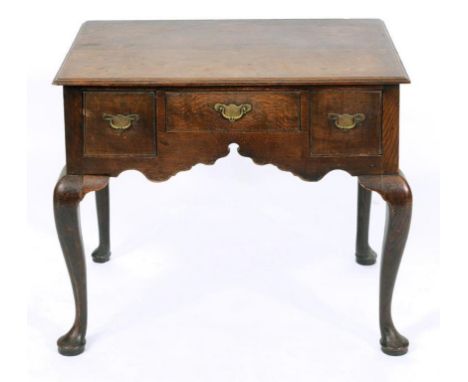 A George III oak lowboy, having three frieze drawers above a shaped apron, on cabriole front legs with pad feet, 75 cm wide  