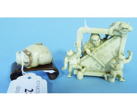 A Japanese ivory okimono, of Shoki the demon slayer and three demons, signed, 6 cm high, a cat netsuke, and a hardwood stand 