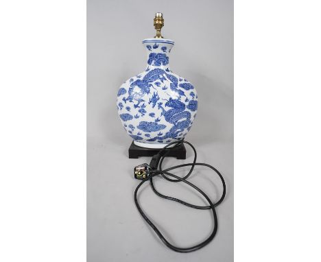 A Chinese blue and white dragon design porcelain moon vase table lamp, on lacquered base. H.48 W.33 