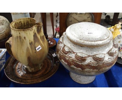 •Nan Mckinnell stoneware pot on stand with lid, a brown glazed dish on three feet, both signed and a jug in light brown glaze