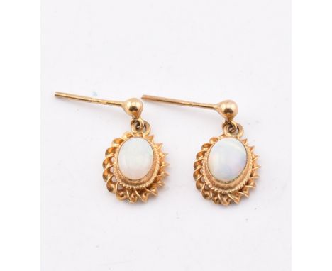 A pair of hallmarked 9ct gold and opal pendant earrings AF. The 9ct yellow gold earrings having a millegrain set oval opal ca
