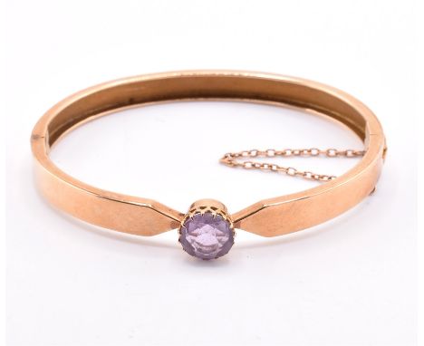 A 15ct gold and amethyst bangle. The 15ct gold bangle set with a single claw mounted round cut amethyst to push clasp with sa