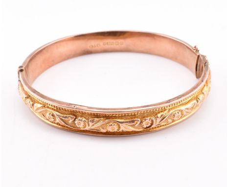 An Edwardian hallmarked 9ct gold engraved hinged bangle. The 9ct bi-colour gold bangle having a central yellow gold engraved 