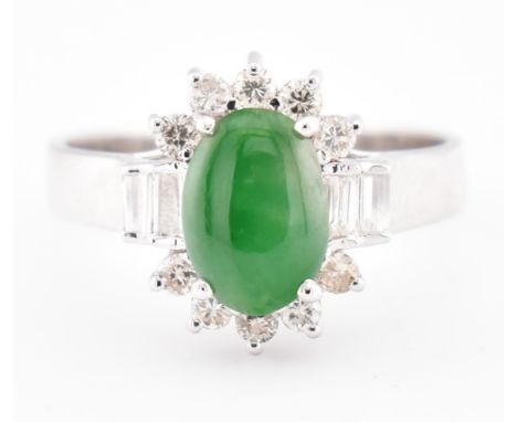 An 18ct white gold jade and diamond halo ring. The 18ct white gold ring set with a central oval jade cabochon having baguette