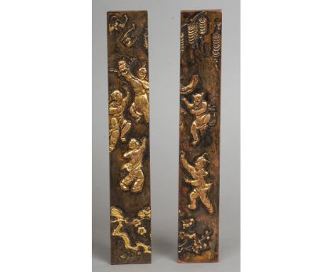 A pair of Chinese bronze and gilded scroll weights
Both worked with dancing children and symbols of good fortune.  25 cm long