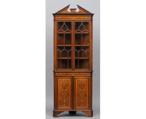 An Edwardian inlaid mahogany standing corner cabinet
The broken dentil moulded cornice above twin astragal glazed doors enclo