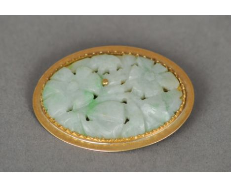 A carved jade brooch
Of pierced floral form, mounted in a gold setting, indistinctly marked to reverse 750.  3.5 cm wide. CON