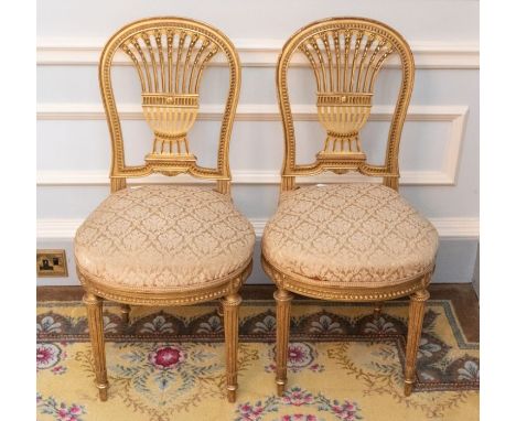 A pair of French Louis XVI style gilt wood and upholstered saloon chairs, circular backs with ornate splats, upholstered seat