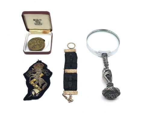 Four miscellaneous items, comprising:- a magnifying glass with a peweter hand handle, a R.E.M.E. regimental insignia, a black