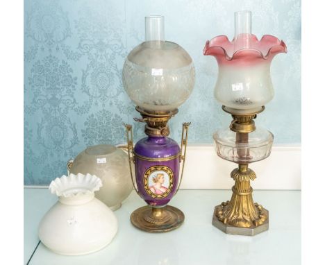 A pair of early 20th century paraffin lamps, one in a neoclassic style, the other art deco, with two additional glass shades 