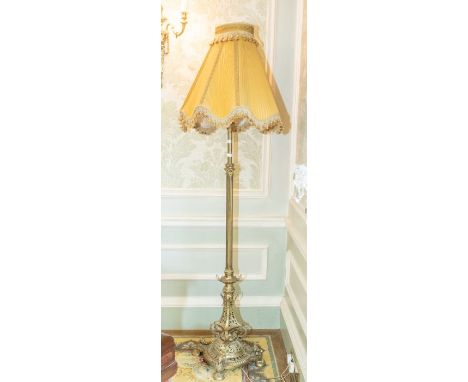 A early 20th century Georgian style brass floor light with fluted column, ornate foliate pierced base raised on four cherub f