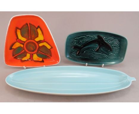A group of twentieth century Poole Pottery wares. To include: a dolphin dish, a stylised floral dish and a long serving dish.